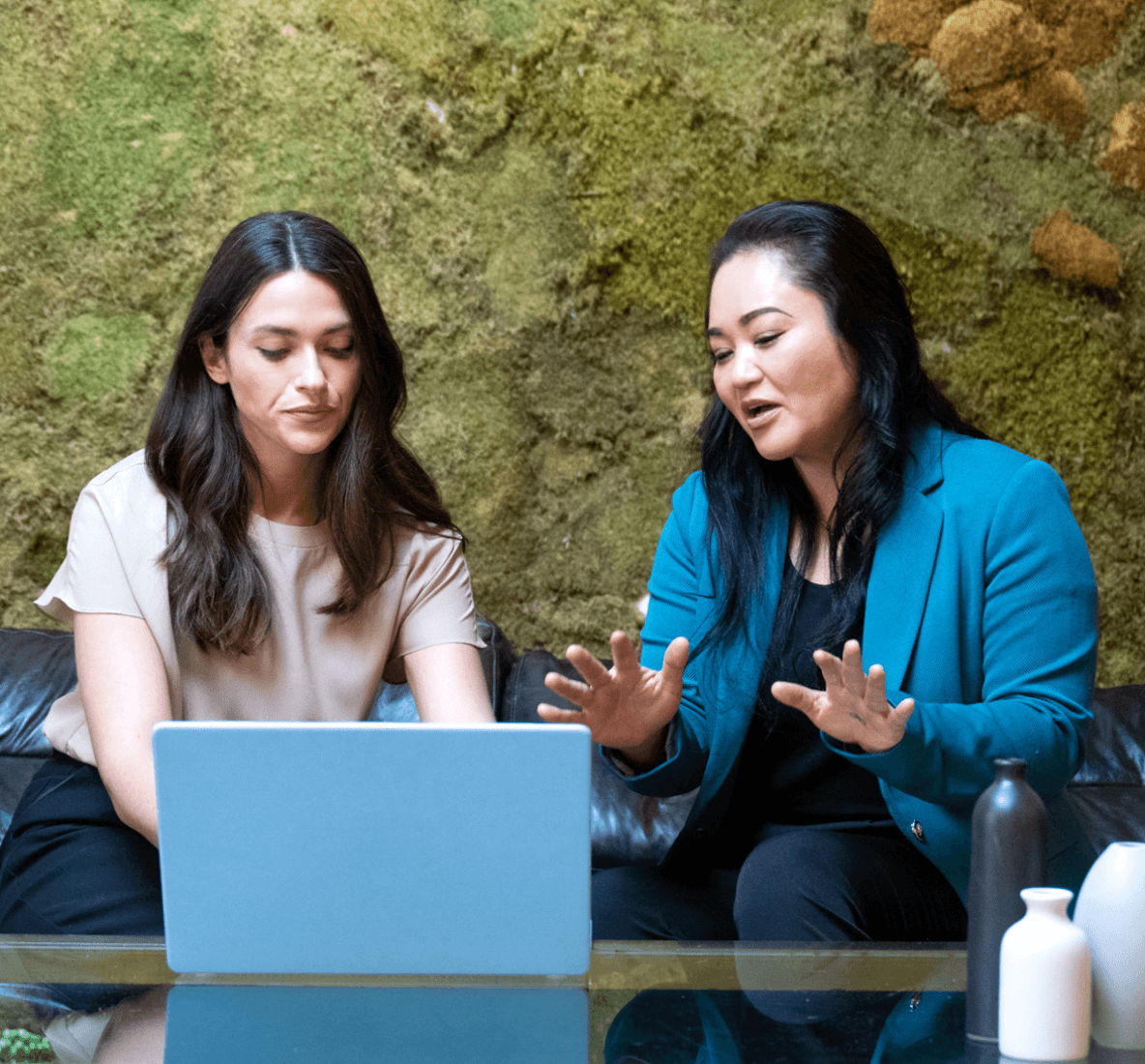 Imagen de dos mujeres sentadas frente a un portátil conversando.