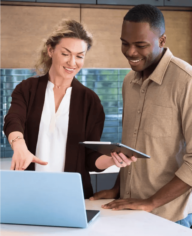 Homem e mulher sorrindo enquanto olham para o laptop.