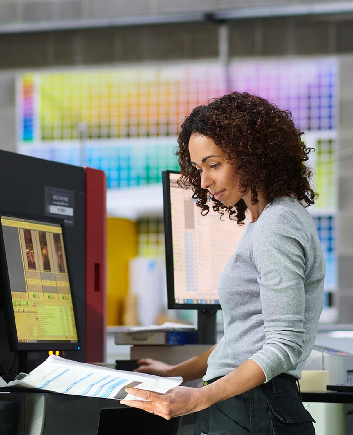 Image of woman working at a desk with a computer and a set of paper.
