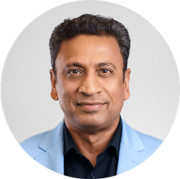 Headshot of a smiling man with dark hair wearing a light blue blazer.